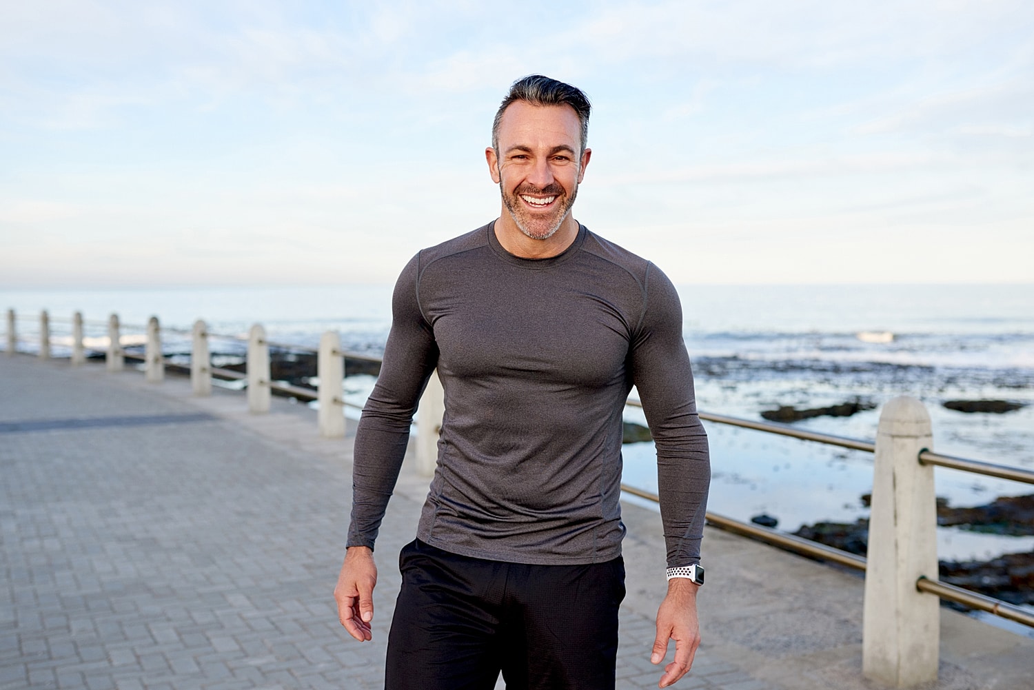 Man smiling by the seaside in athletic wear.