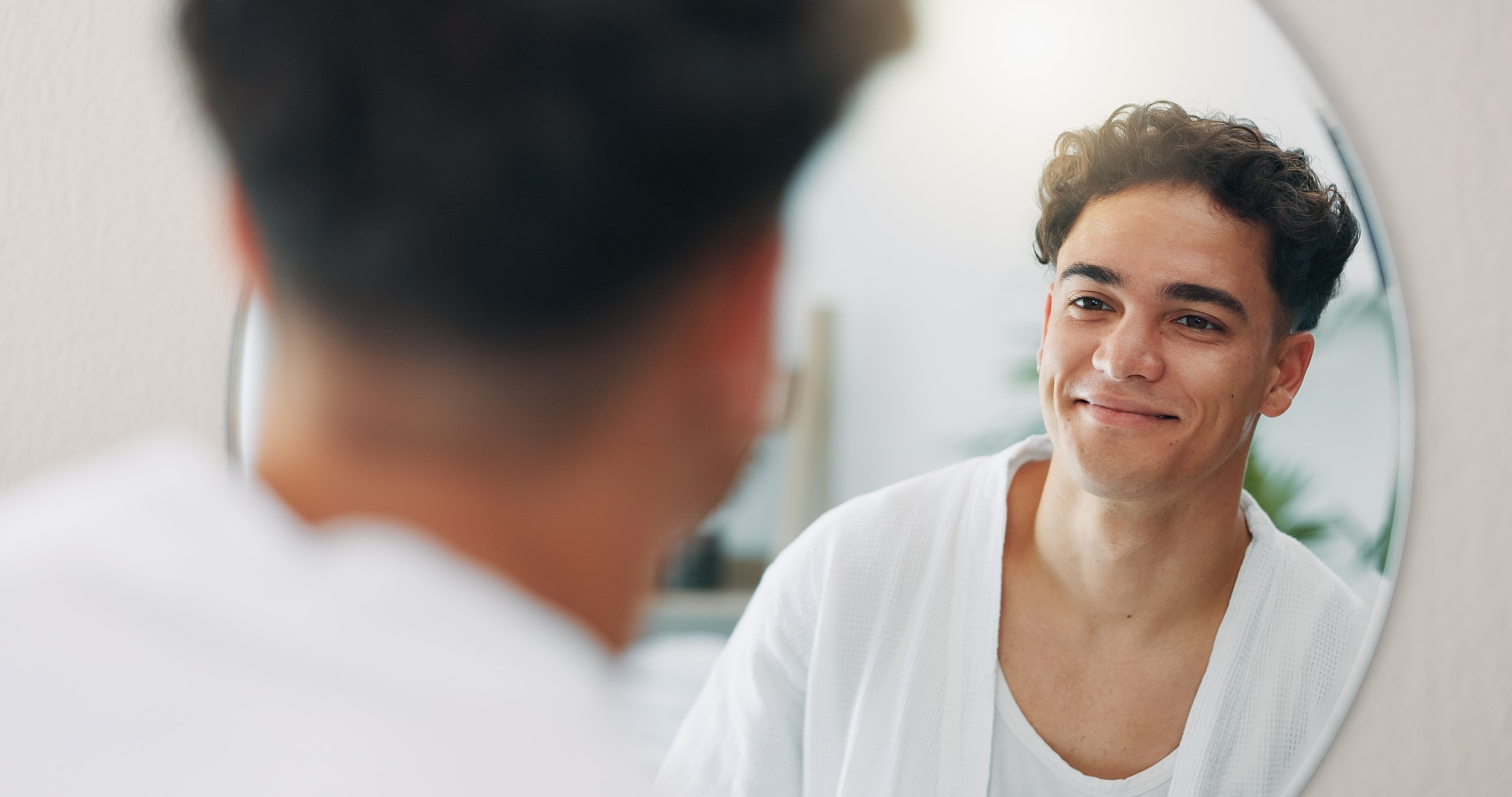 Smiling man looking into mirror at home.